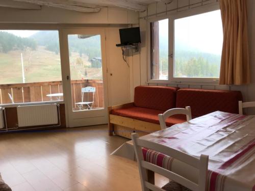 a room with a couch and a chair and a balcony at Studio pied de pistes balcon et vue montagne in Montgenèvre