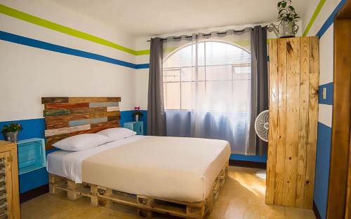 a bedroom with a bed with blue and green stripes at The Purpose Hostel in Antigua Guatemala