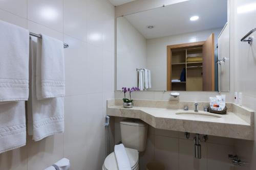 uma casa de banho branca com um lavatório e um WC em Matiz Jaguariúna em Jaguariúna