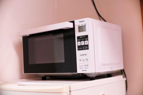 a microwave oven sitting on top of a refrigerator at Takaraboshi room 201 Sannomiya 10 min in Kobe