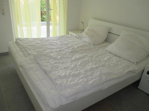un letto con lenzuola e cuscini bianchi in una camera da letto di Homal a Costanza