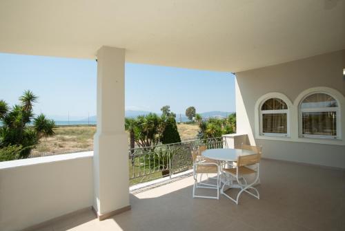 a patio with a table and chairs on a balcony at The Villa of the Winds in Néa Kíos