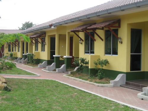żółty budynek z chodnikiem obok niego w obiekcie New Dawn for Langkawi w mieście Kampung Padang Masirat