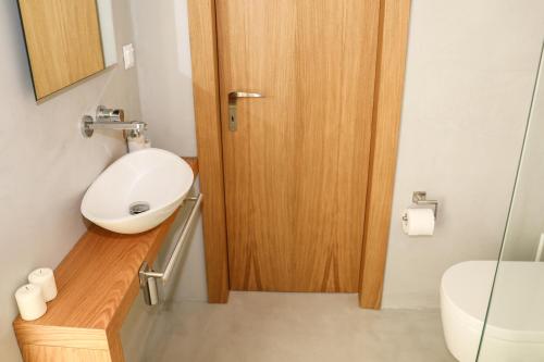 a bathroom with a toilet and a wooden door at Thalasses Villas Skiathos in Skiathos Town
