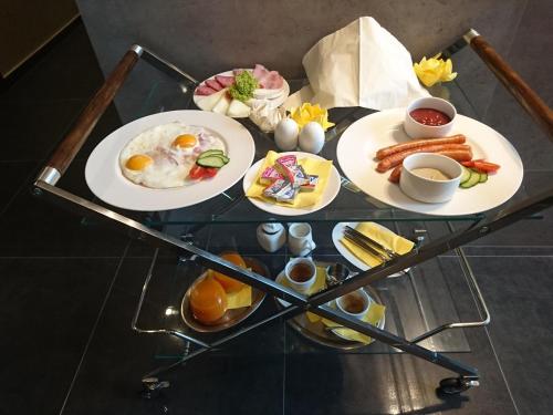 a glass table with two plates of breakfast food on it at Penzión v Inom Svete in Žilina