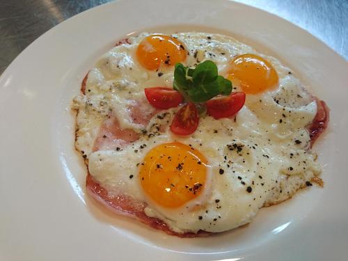 a plate of eggs with tomatoes and a garnishment at Penzión v Inom Svete in Žilina