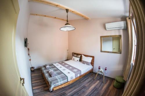 ein kleines Schlafzimmer mit einem Bett und einem Spiegel in der Unterkunft The Old House guest rooms and apartament in Plowdiw