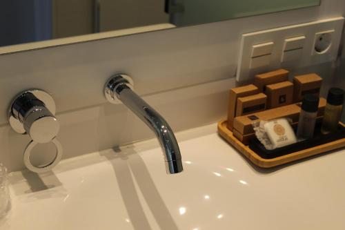 a bathroom sink with a faucet and a tray of soap at Salamanca Suites Libertad in Salamanca
