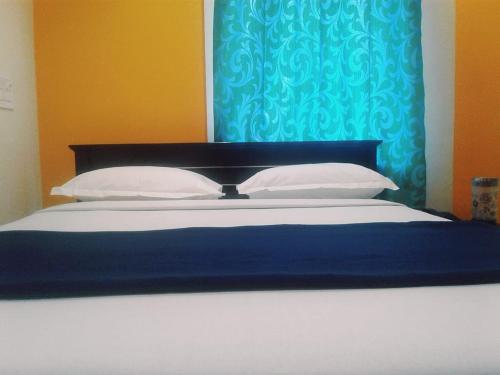 a bed with white pillows and a blue curtain at Hotel Royal Inn in Hiriyūr