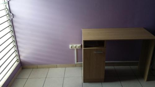 a desk in a room with a purple wall at Chambre n°1 dans la maison du bonheur in Les Abymes