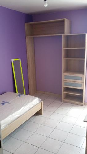 a bedroom with a bunk bed and a purple wall at Chambre n°1 dans la maison du bonheur in Les Abymes