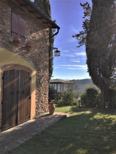 a stone house with a wooden door and a yard at Podere Casanova in Montespertoli