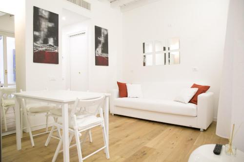 un soggiorno bianco con tavolo bianco e divano di Amazing, new & fully furnished studio in Duomo a Milano