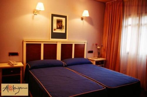 een slaapkamer met een blauw bed en een raam bij Hostal Atalaya in Minas de Ríotinto