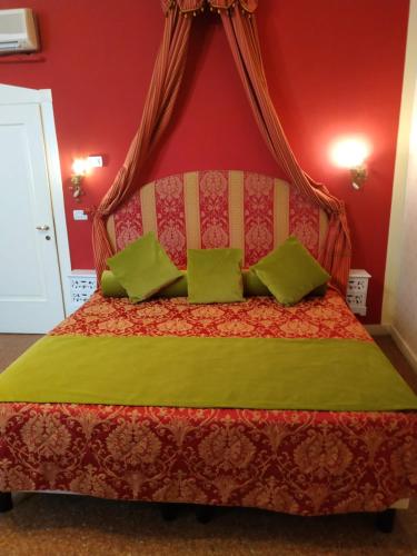 een rode slaapkamer met een bed met groene kussens bij Alloggi Acquavita - checkin at "Alloggi SS Giovanni e Paolo" in Venetië