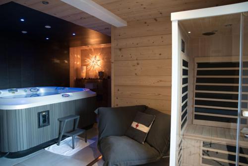 a bathroom with a tub and a chair in a room at Chalet 4M Les Carroz et son Spa in Les Carroz d'Araches