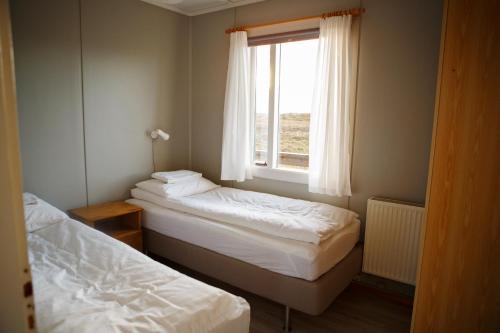 2 Betten in einem kleinen Zimmer mit Fenster in der Unterkunft Hestaland Riverside Cottage in Staðarhús