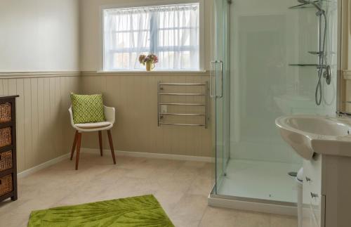 a bathroom with a shower and a sink and a chair at The Whitehouse of Marybank in Nelson
