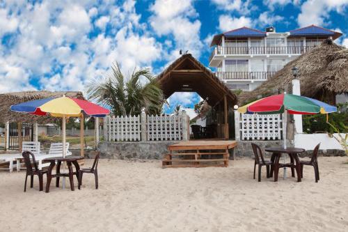 duas mesas e cadeiras com guarda-sóis na praia em Elegant Green Beach Resort em Trincomalee