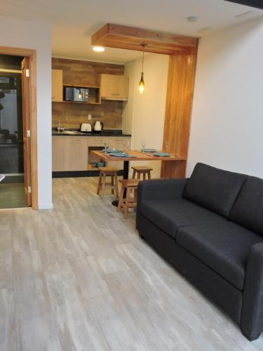 a living room with a black couch and a kitchen at EcoLofts Croacia 1028 in Punta Arenas