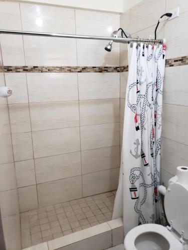 a bathroom with a shower curtain and a toilet at Jardin del Mar Guesthouse in Hatillo