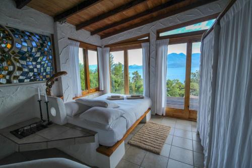 a bedroom with a bed and a large window at Lush Atitlán in San Marcos La Laguna