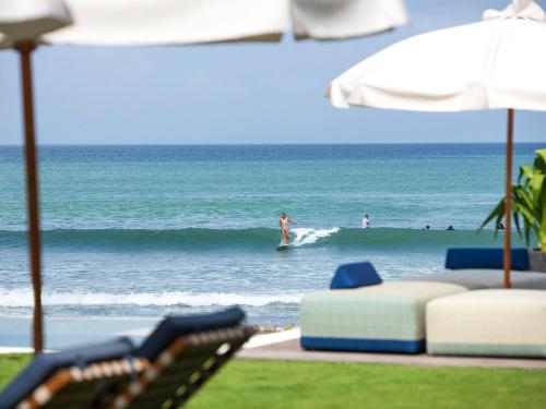 a group of people surfing on a wave in the ocean at Noku Beach House by Elite Havens in Seminyak