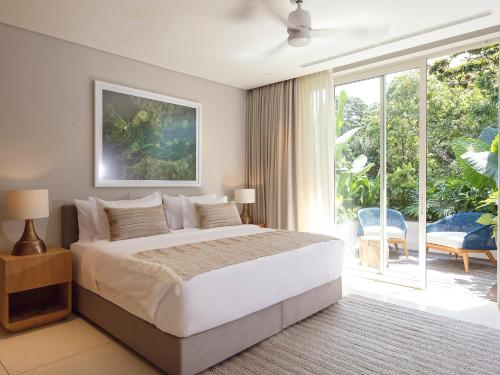 a bedroom with a large bed and a large window at Noku Beach House by Elite Havens in Seminyak