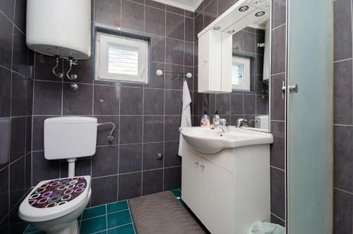 a bathroom with a toilet and a sink and a mirror at Apartment Marija Zdenko in Lopar