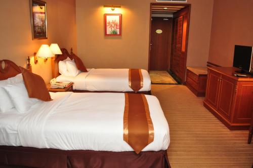 a hotel room with two beds and a television at Mulia Hotel in Bandar Seri Begawan