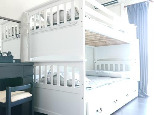 ein weißes Etagenbett in einem Zimmer mit einem Schreibtisch in der Unterkunft Yenn's Marina Inn Zamami Condominium in Zamami