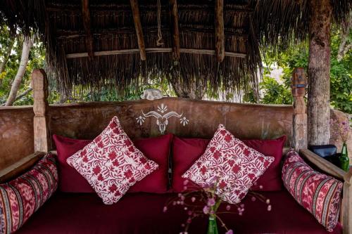 a couch with red and white pillows on it at Utopia Rote Lodge in Nembrala