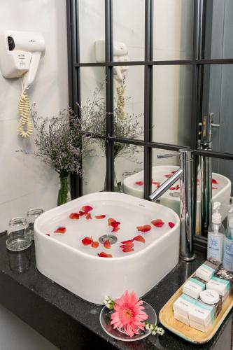 a bathroom with a bath tub with flowers on a counter at Le House Boutique Hotel - 100m to the beach in Da Nang
