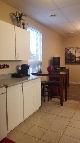 a kitchen with white cabinets and a table and a desk at Studio Cozy #12 by Amazing Property Rentals in Gatineau
