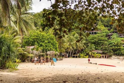 a group of people on a beach with palm trees at Mai Pen Rai Bungalows in Than Sadet Beach