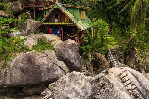 a small house sitting on top of some rocks at Mai Pen Rai Bungalows in Than Sadet Beach