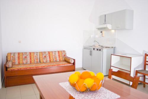a living room with a table with a bowl of oranges at Garifalo Apartments in Kalyves