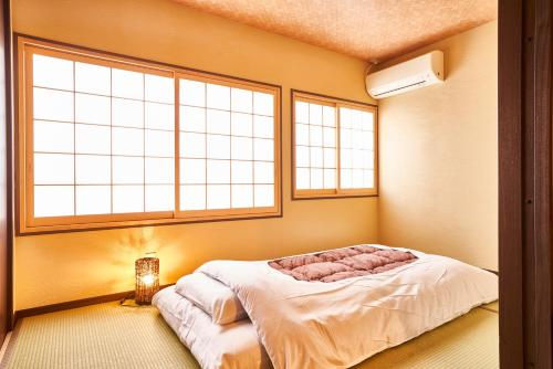 a bedroom with a bed in a room with two windows at Miyazakiya Plus in Kyoto