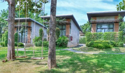a house with two trees and swings in the yard at Casa Foresta Nan in Nan