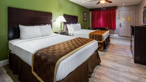 2 Betten in einem Hotelzimmer mit grünen Wänden in der Unterkunft Bestway Inn in Kaufman
