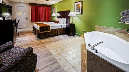 a hotel room with a bed and a bath tub at Bestway Inn in Kaufman
