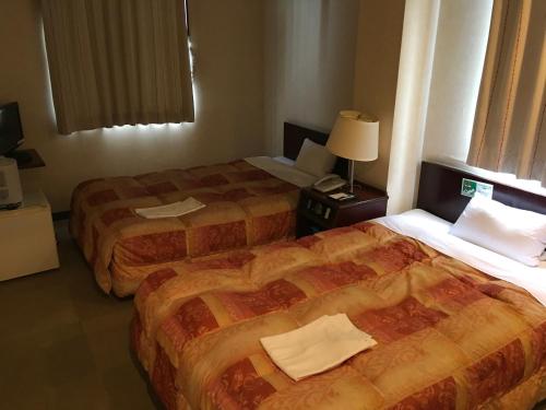 una habitación de hotel con 2 camas y una lámpara en Green Hotel Shimonoseki, en Shimonoseki