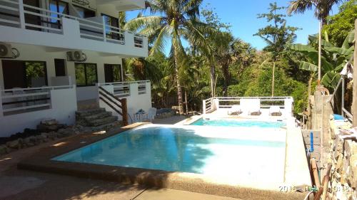 a swimming pool in front of a house at Jalyn's Resort Sabang in Puerto Galera