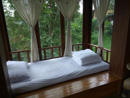 a bed in a room with a large window at Khunyuam Resort in Ban Khun Yuam