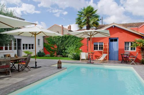 einen Pool mit einem Tisch und Sonnenschirmen neben einem Haus in der Unterkunft La Ferrade Chambres d'Hôtes B&B in Bègles
