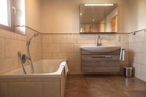 a bathroom with a tub and a sink and a mirror at Ferienhaus am Riedl in Siegsdorf