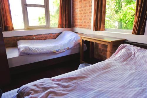 a bedroom with two beds and a desk and windows at Hotel At The End Of The Universe in Nagarkot