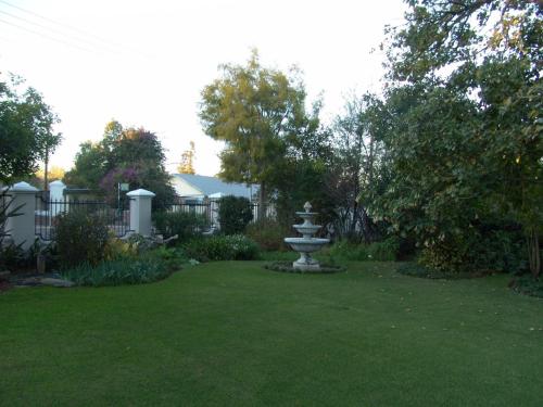 a garden with a fountain in the middle of a yard at La Pension Guest House in Oudtshoorn