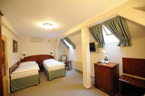 a bedroom with two beds and a table and a television at Hotel Prince de Ligne in Teplice