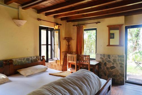 a bedroom with a bed and a table and windows at Hotel At The End Of The Universe in Nagarkot